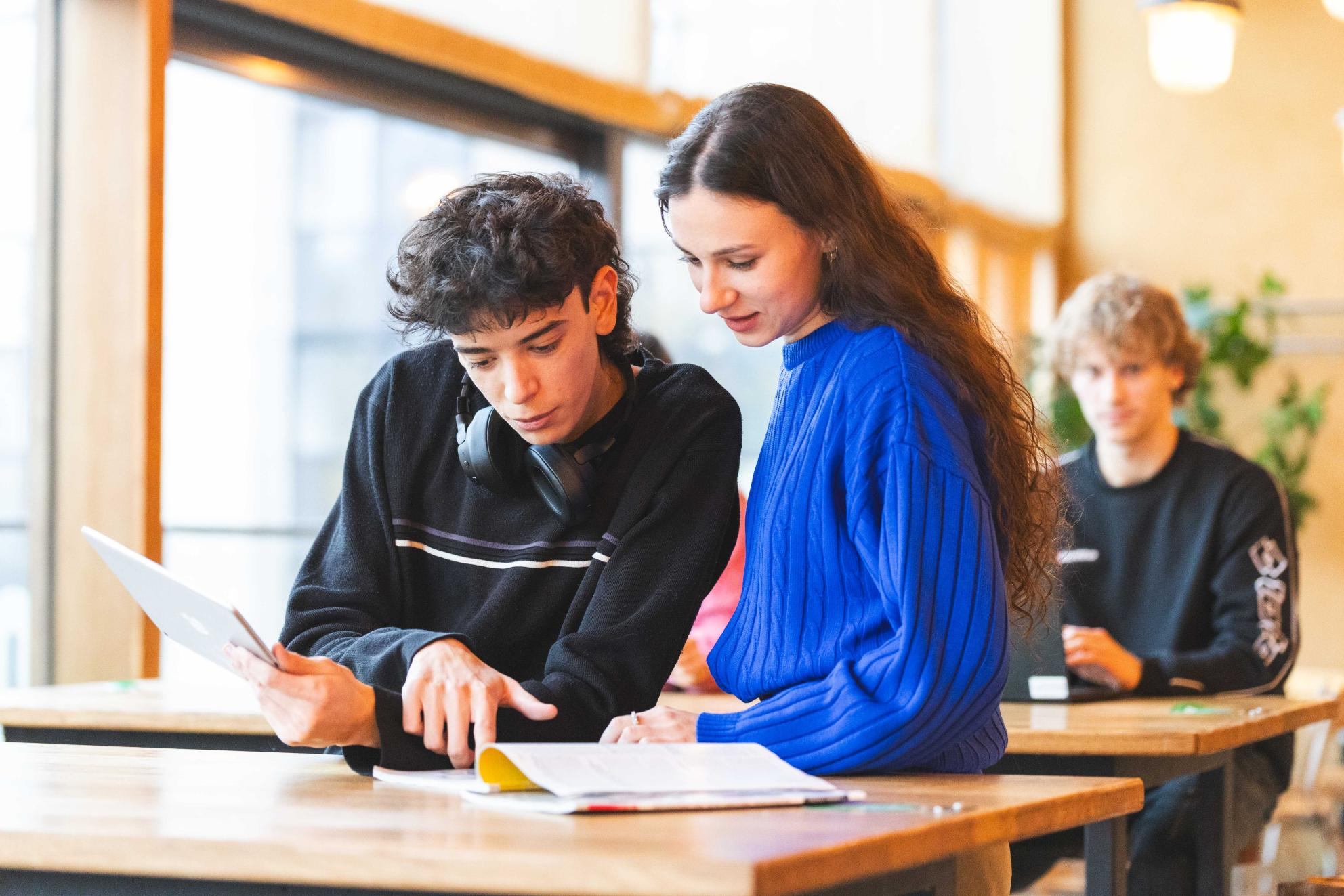A young man and a woman looking at tablets and paper documents
